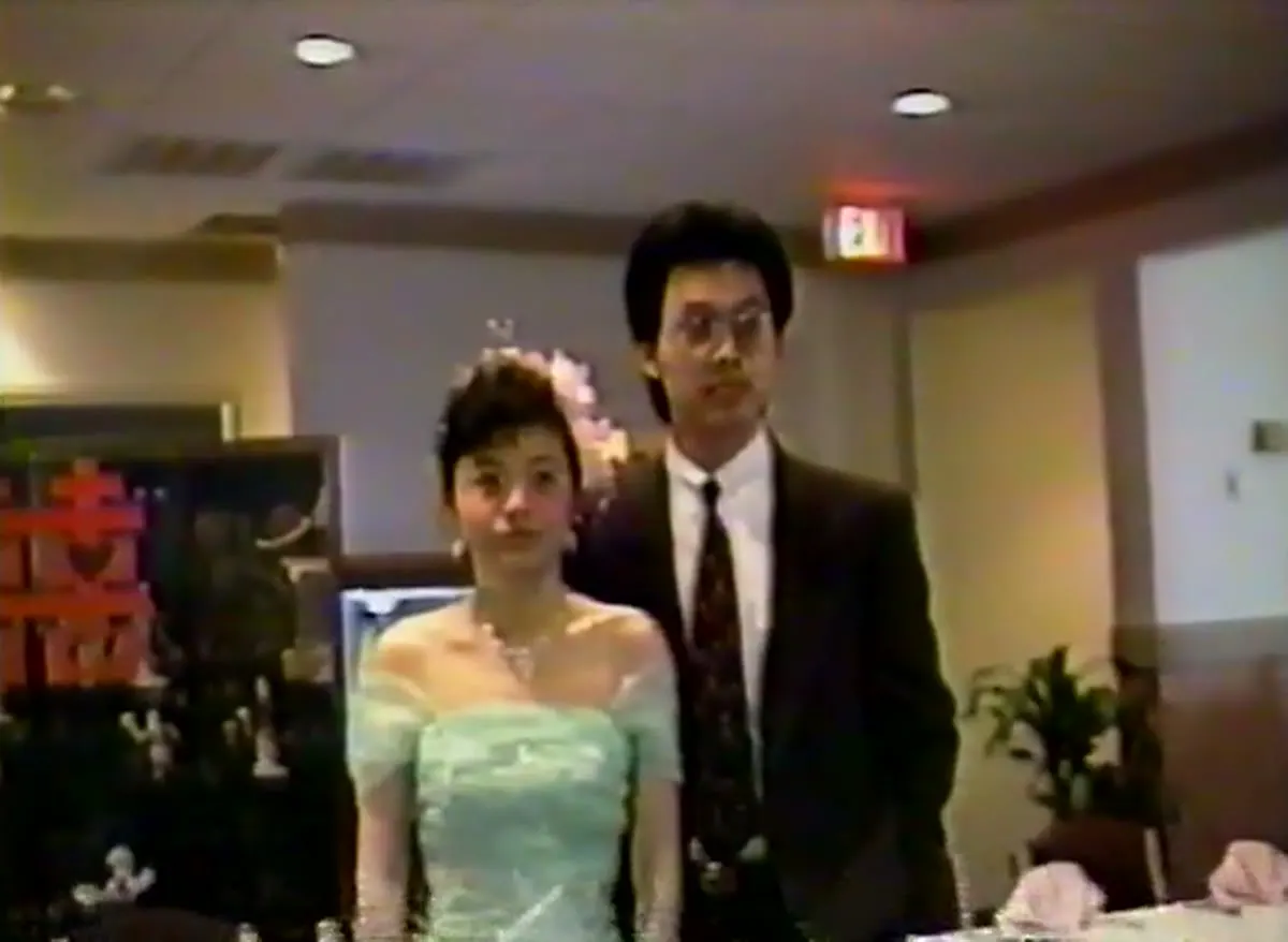 Judy and Jim in front of a red double-happiness sign in the dining room, 1989